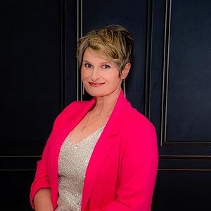 T.L. Johnson, romantic suspense author and founder of Midnight Haven Books, pictured in a vibrant pink blazer and sparkling top. Known for s